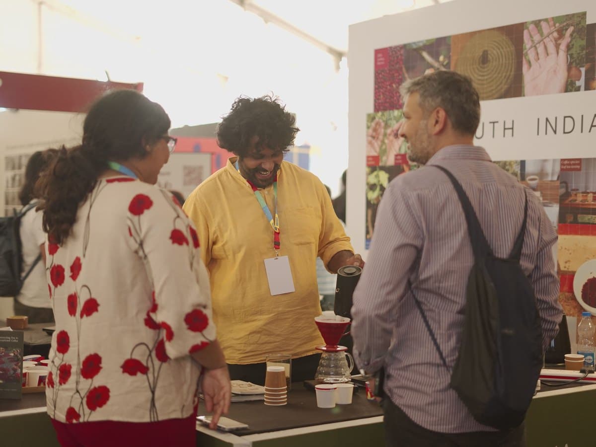 Visitors talking with an exhibitor brewing pour-over at a booth